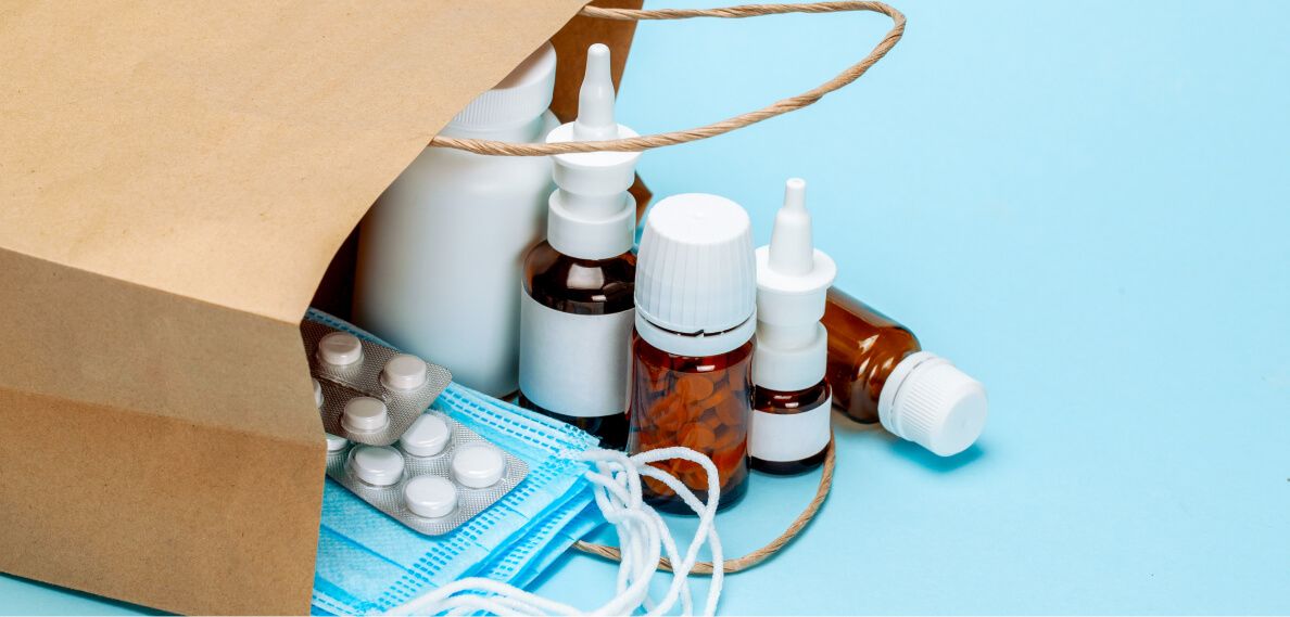 Arzneimittel und Masken auf einem Tisch mit brauner Tüte