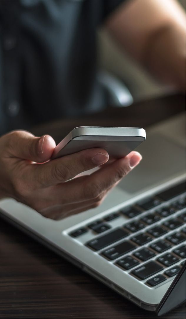 Nahaufnahme eines Smartphones und einem Laptop im Hintergrund